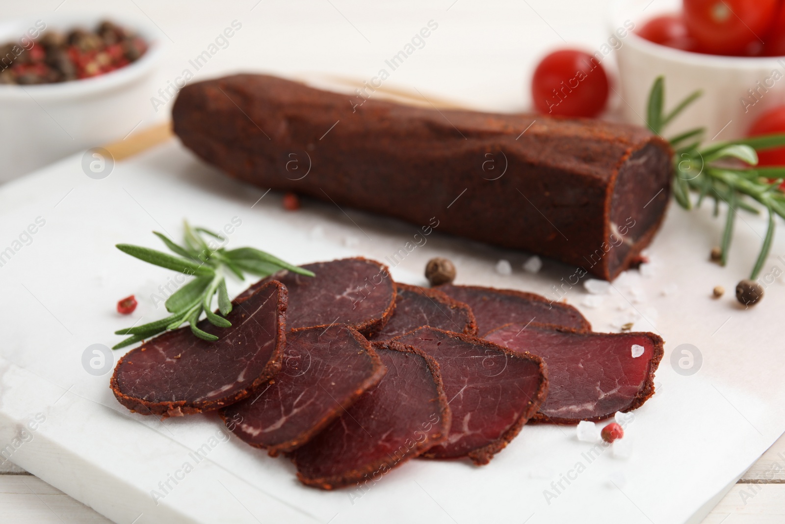 Photo of Delicious dry-cured beef basturma with rosemary and spices on table, closeup