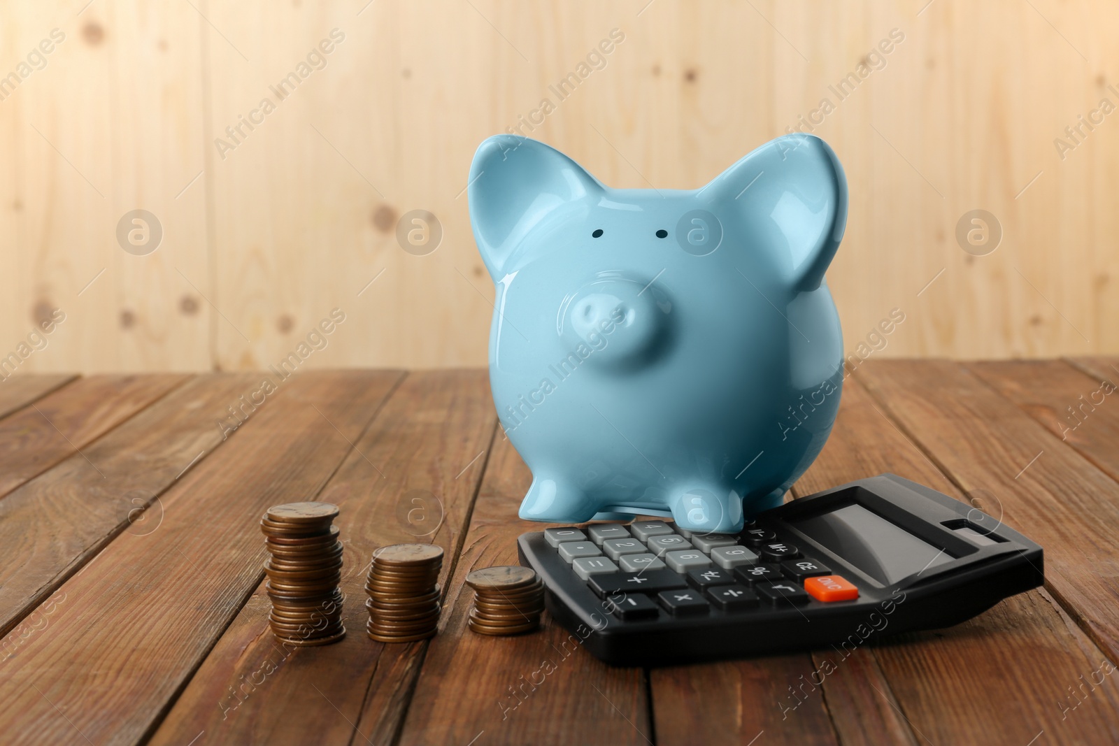 Photo of Calculator, coins and piggy bank on wooden table