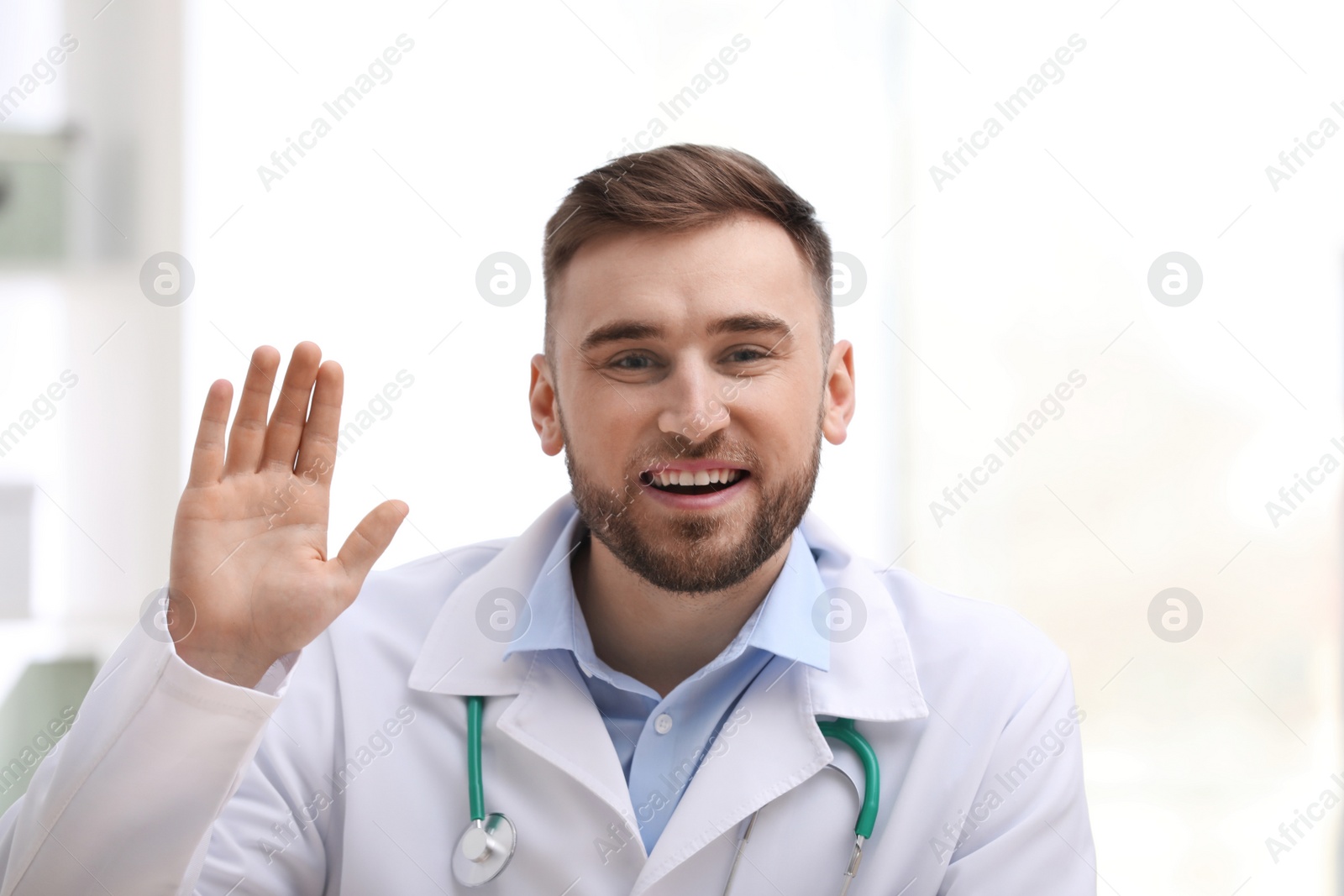 Photo of Male doctor using video chat at workplace, view from camera perspective