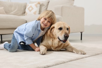 Cute little child with Golden Retriever on floor at home. Adorable pet