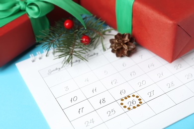 Calendar with marked Boxing Day date and gifts on light blue background, closeup