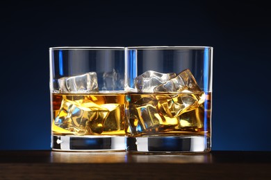 Photo of Whiskey with ice cubes in glasses on table, closeup