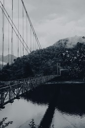 Image of Beautiful view on rusty metal bridge over river in mountains. Black and white effect