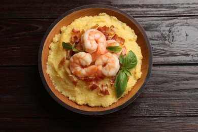 Fresh tasty shrimps, bacon, grits and basil in bowl on wooden table, top view