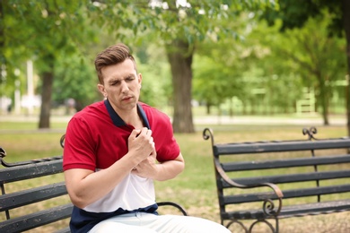 Photo of Young man having chest pain in park. Heart attack