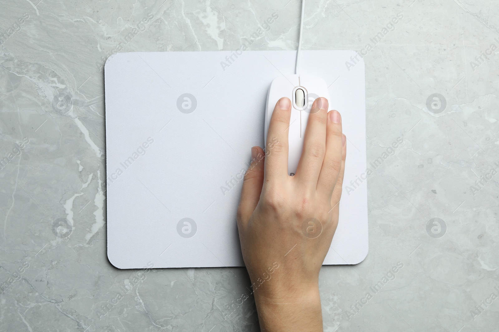 Photo of Woman using wired computer mouse on light grey marble table, top view. Space for text