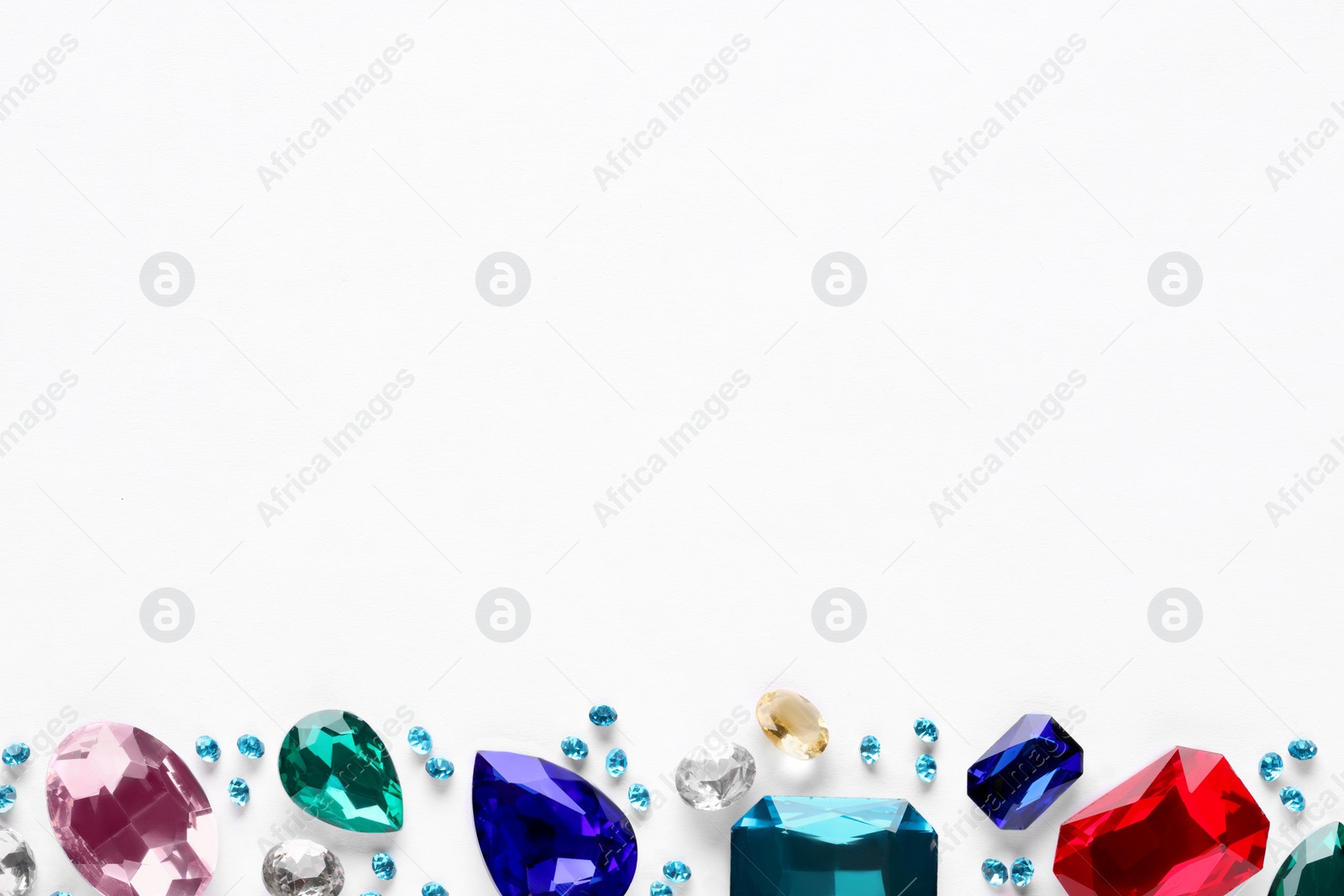 Photo of Different beautiful gemstones for jewelry on white background, top view. Space for text