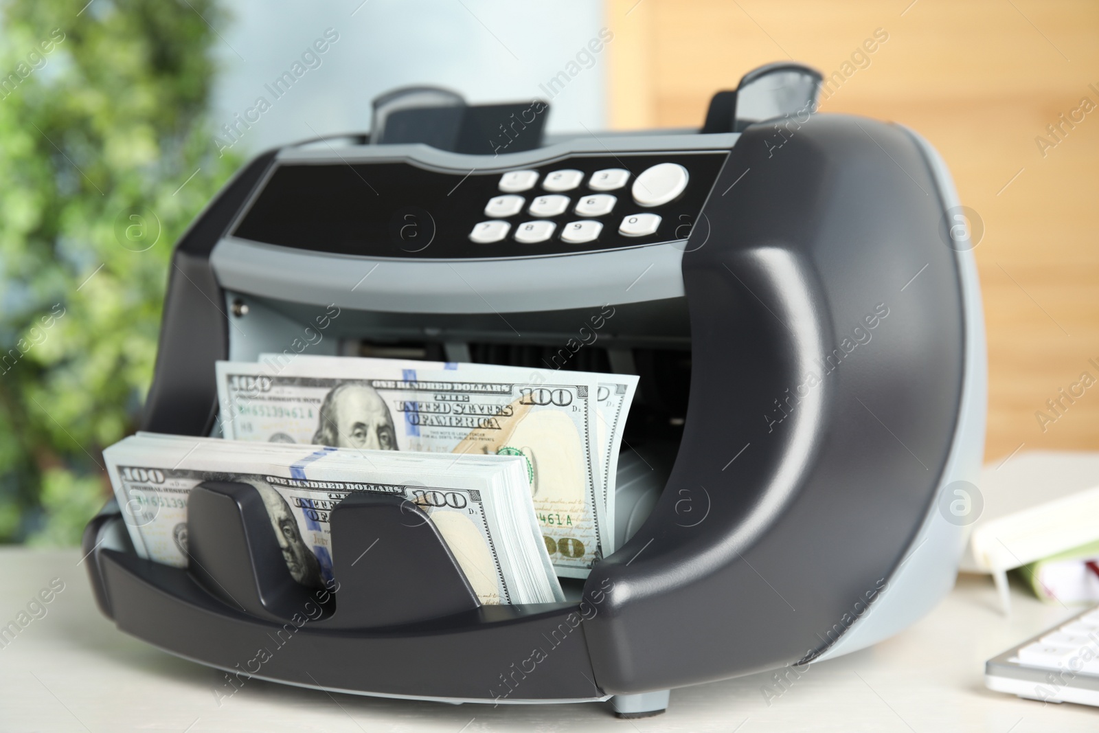 Photo of Modern electronic bill counter with money on table indoors, closeup