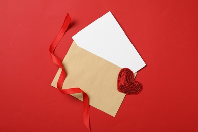 Blank card, decorative heart and ribbon on red background, flat lay with space for text. Valentine's Day celebration