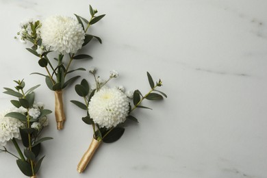 Photo of Small stylish boutonnieres on white marble table, flat lay. Space for text