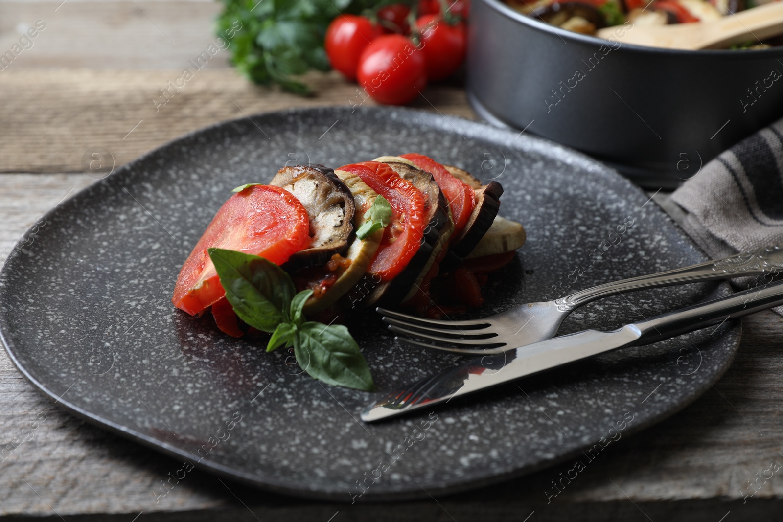 Photo of Delicious ratatouille served with basil on wooden table, closeup