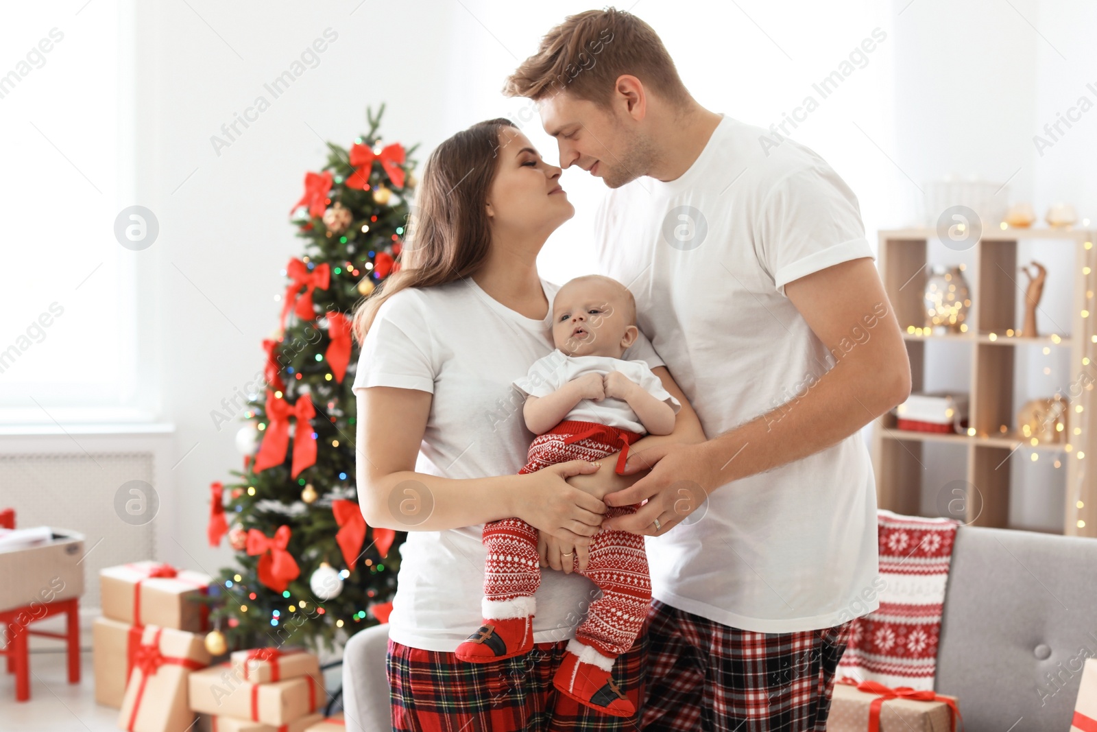 Photo of Happy couple with baby celebrating Christmas together at home