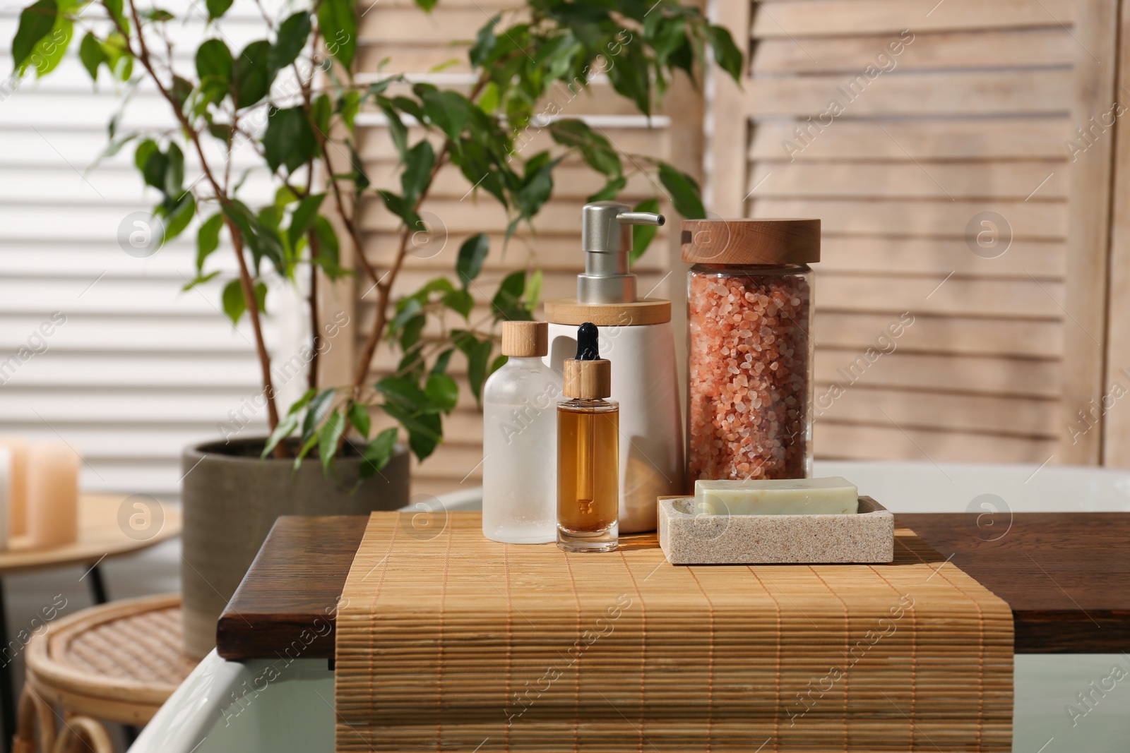 Photo of Wooden tray with spa products on bath tub in bathroom. Space for text