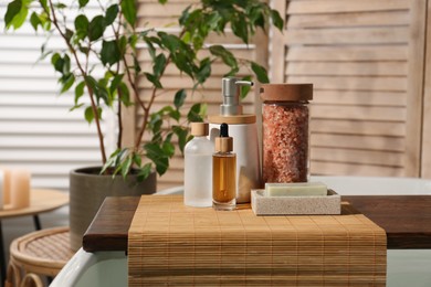 Photo of Wooden tray with spa products on bath tub in bathroom. Space for text