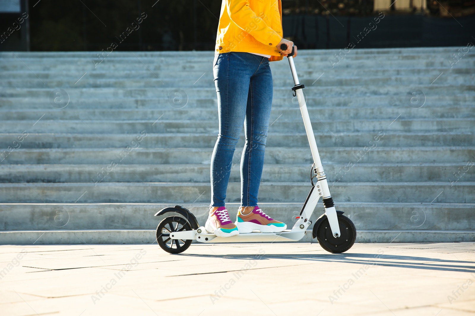 Photo of Woman riding electric kick scooter outdoors on sunny day