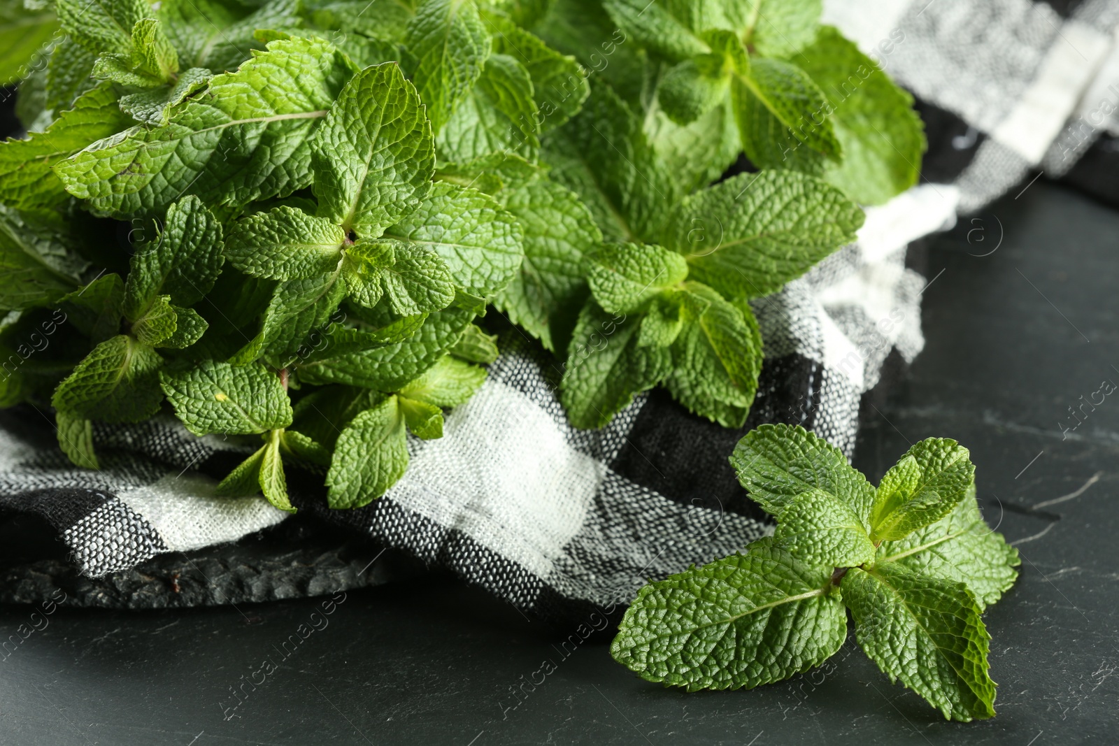 Photo of Fresh green mint leaves on black table, closeup