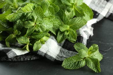 Fresh green mint leaves on black table, closeup