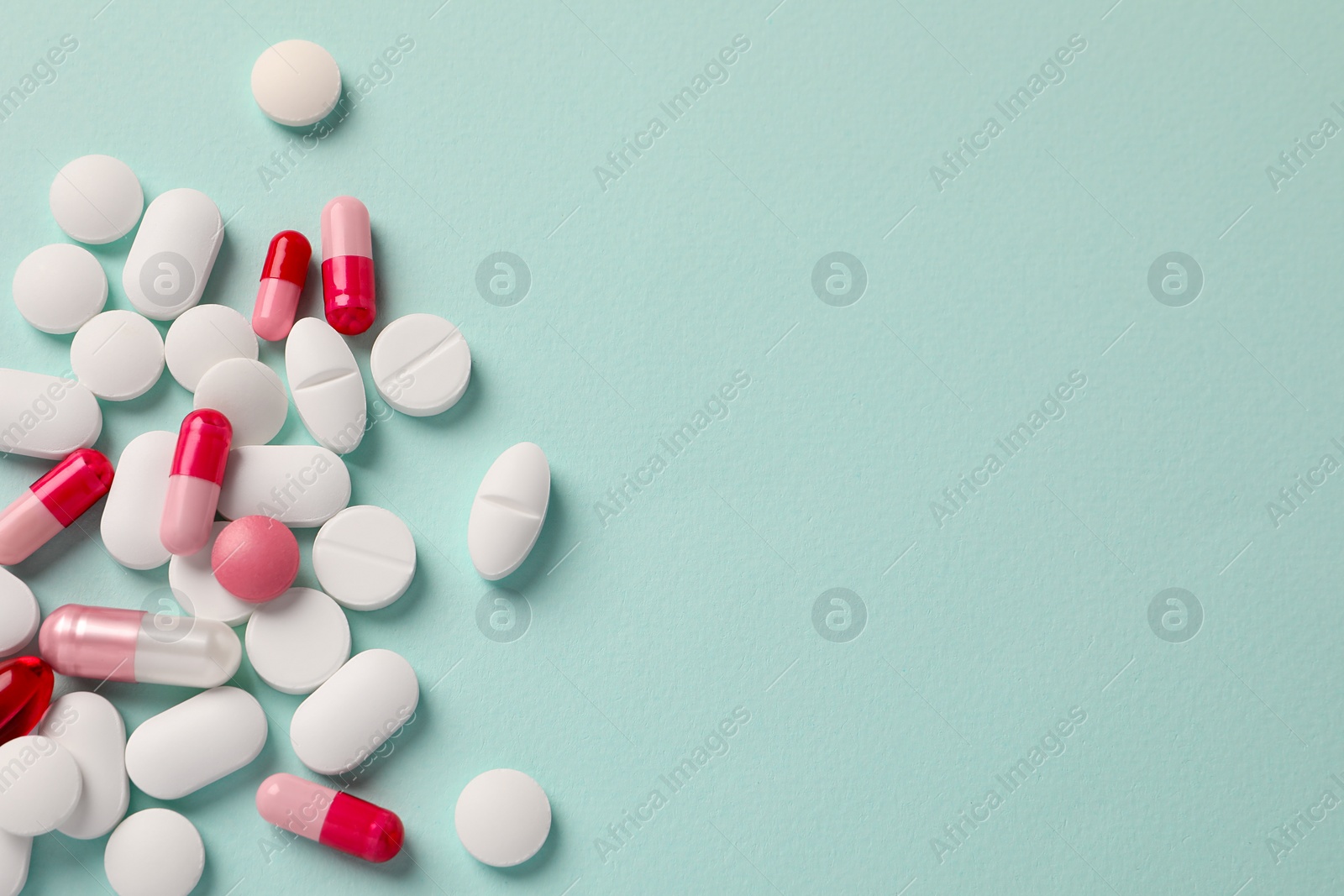 Photo of Many different pills on mint background, flat lay. Space for text