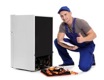 Photo of Male technician with clipboard and tools near broken refrigerator on white background