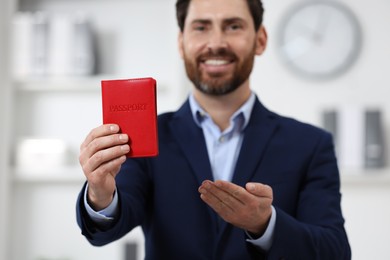 Photo of Immigration. Happy man with passport indoors, selective focus