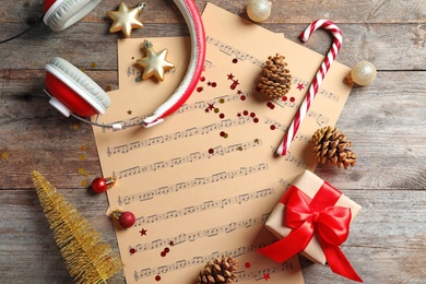 Photo of Flat lay composition with Christmas decorations, music sheets and headphones on wooden background