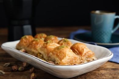 Photo of Delicious baklava with pistachios and scattered nuts on wooden table, closeup