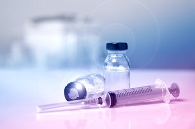 Image of Syringe and vials on table against blurred background