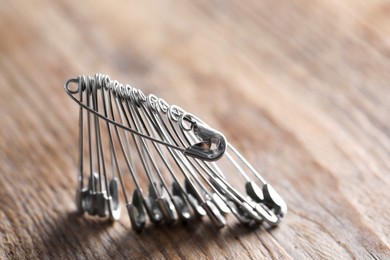 Photo of Many safety pins on wooden table, closeup