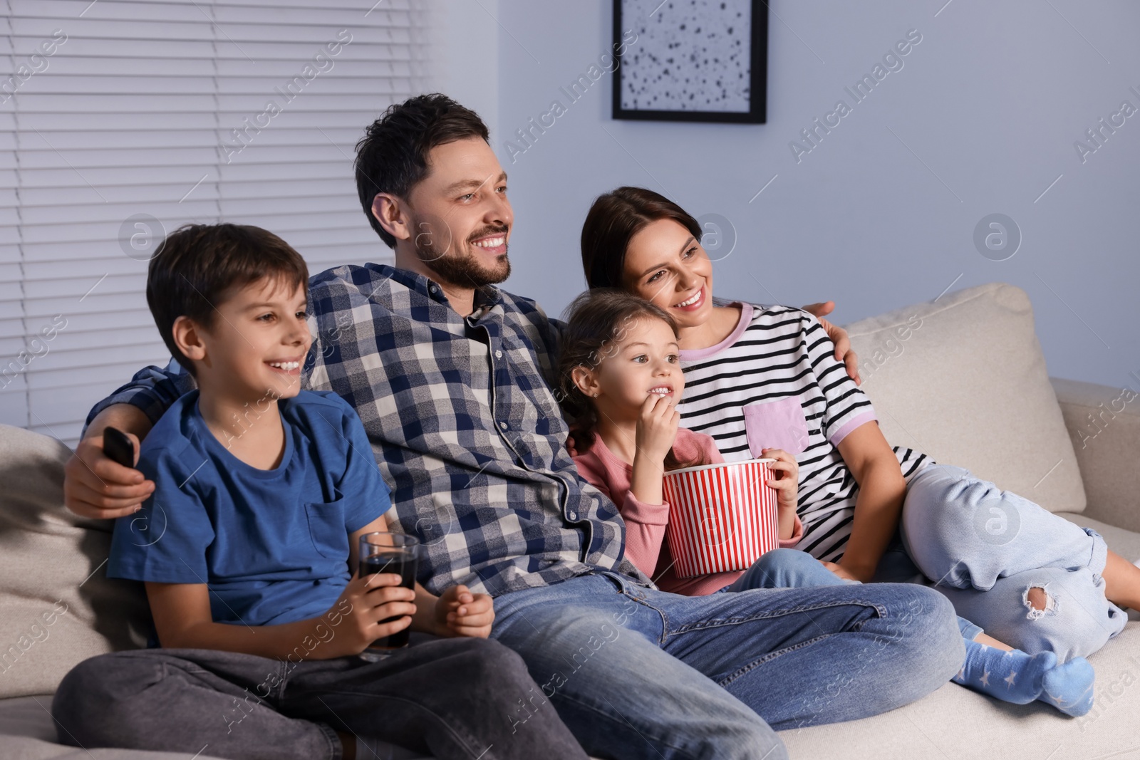 Photo of Happy family watching TV at home in evening