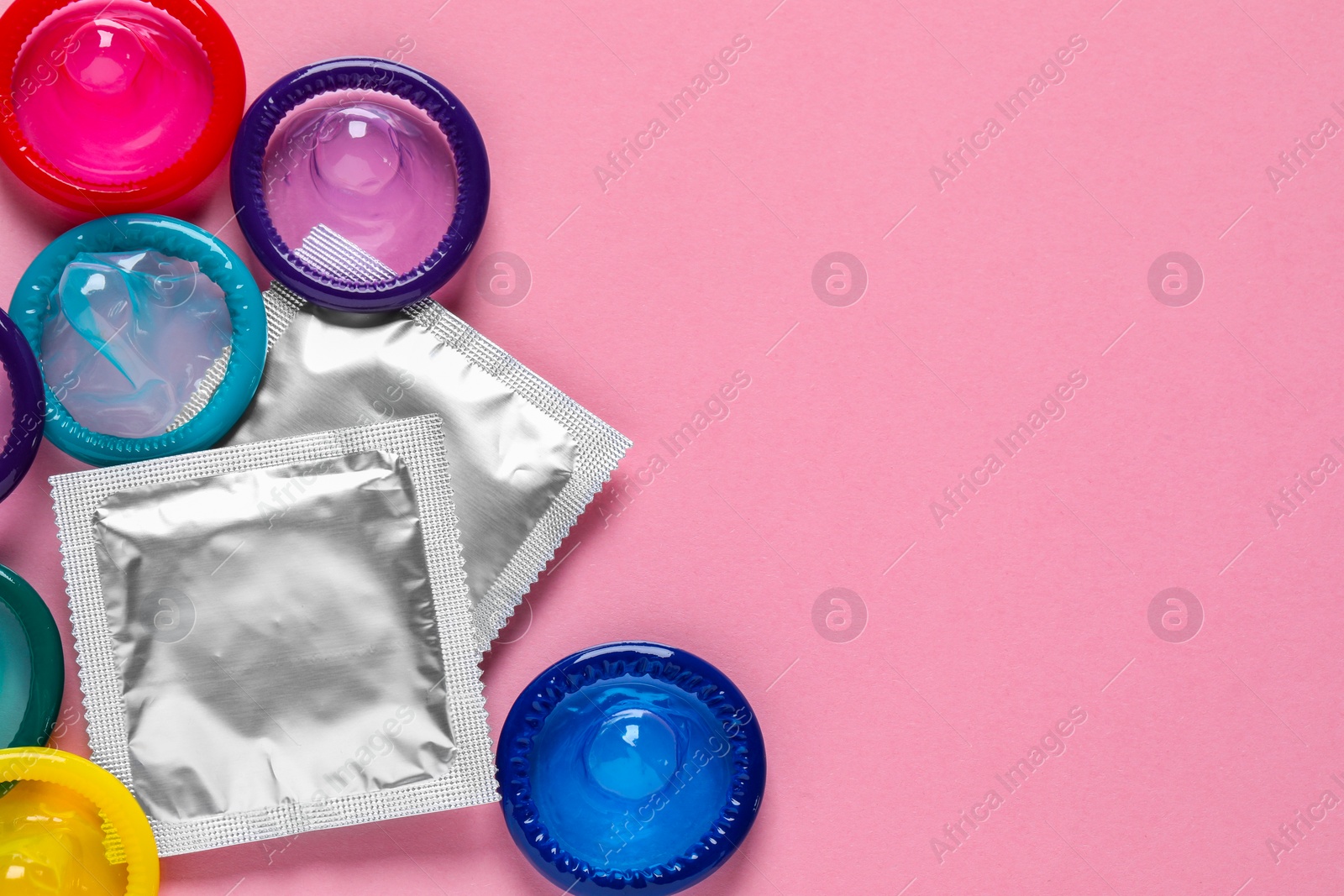 Photo of Condoms on pink background, flat lay. Space for text