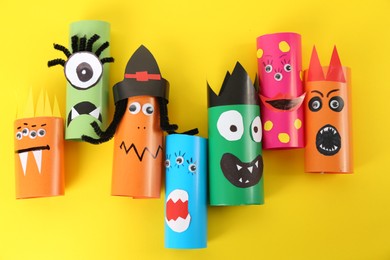 Photo of Funny monsters on yellow background, flat lay. Halloween decoration