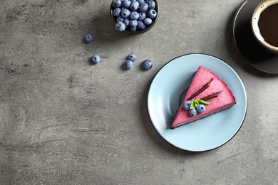 Photo of Flat lay composition with piece of tasty blueberry cake and space for text on gray table