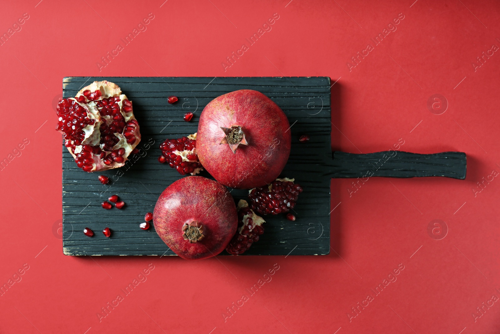 Photo of Wooden board with ripe pomegranates on color background, top view