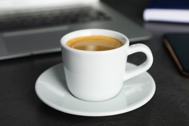 Photo of Coffee Break at workplace. Cup of hot espresso on grey table