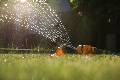 Automatic sprinkler watering green grass on sunny day in garden. Irrigation system