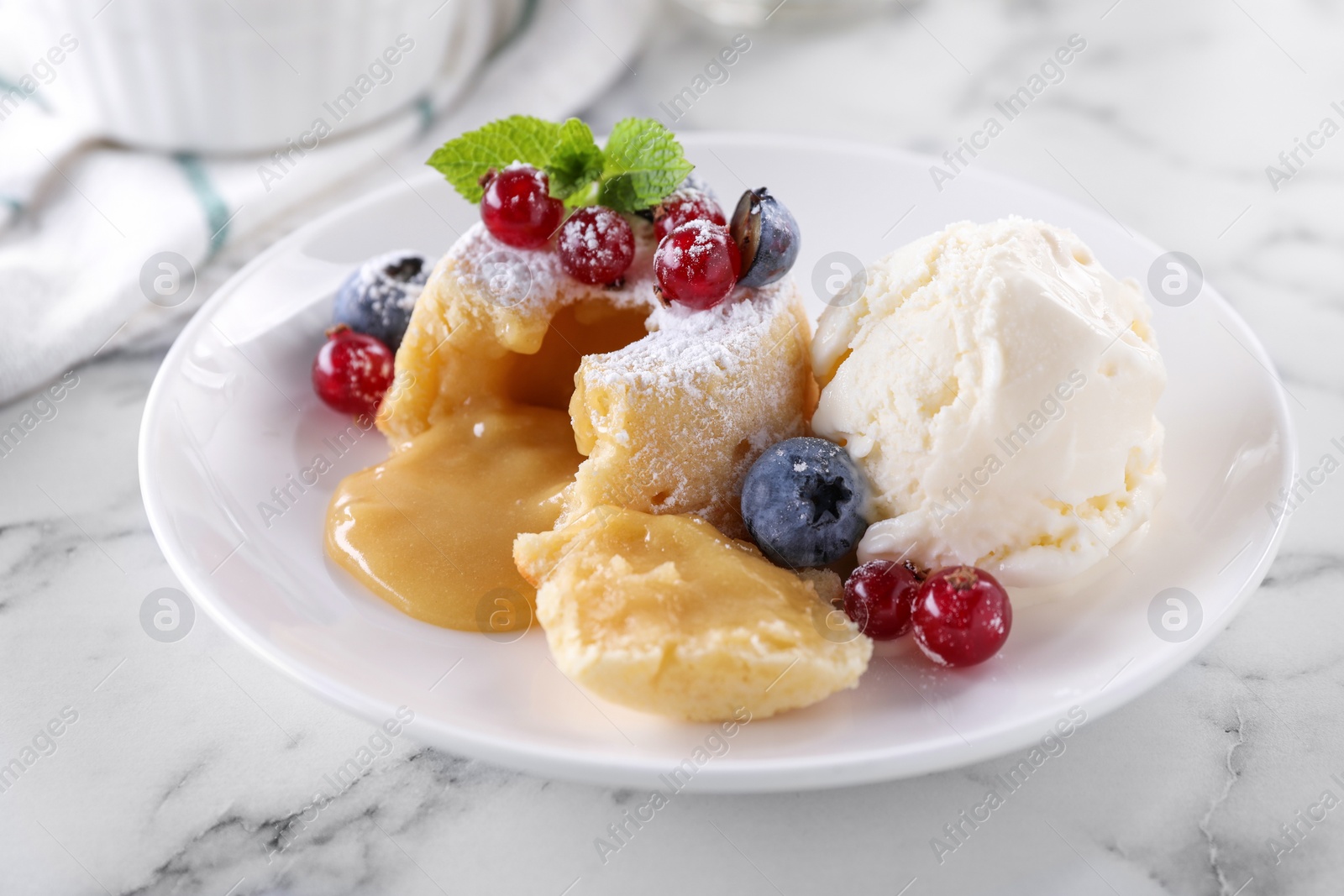 Photo of Tasty vanilla fondant with white chocolate, berries and ice cream on white marble table, closeup