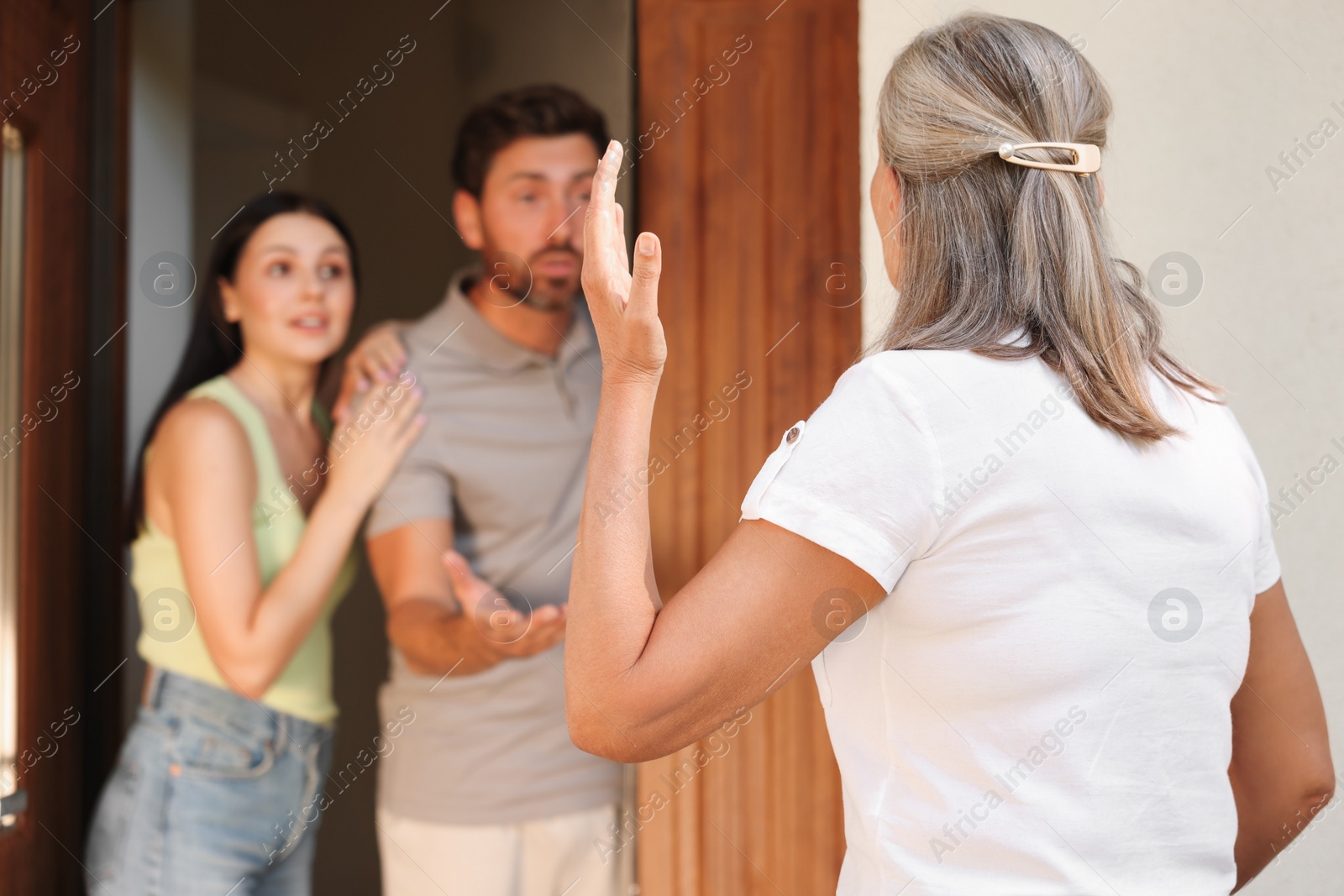 Photo of Neighbour`s quarrel. Senior woman visiting emotional young couple outdoors, selective focus