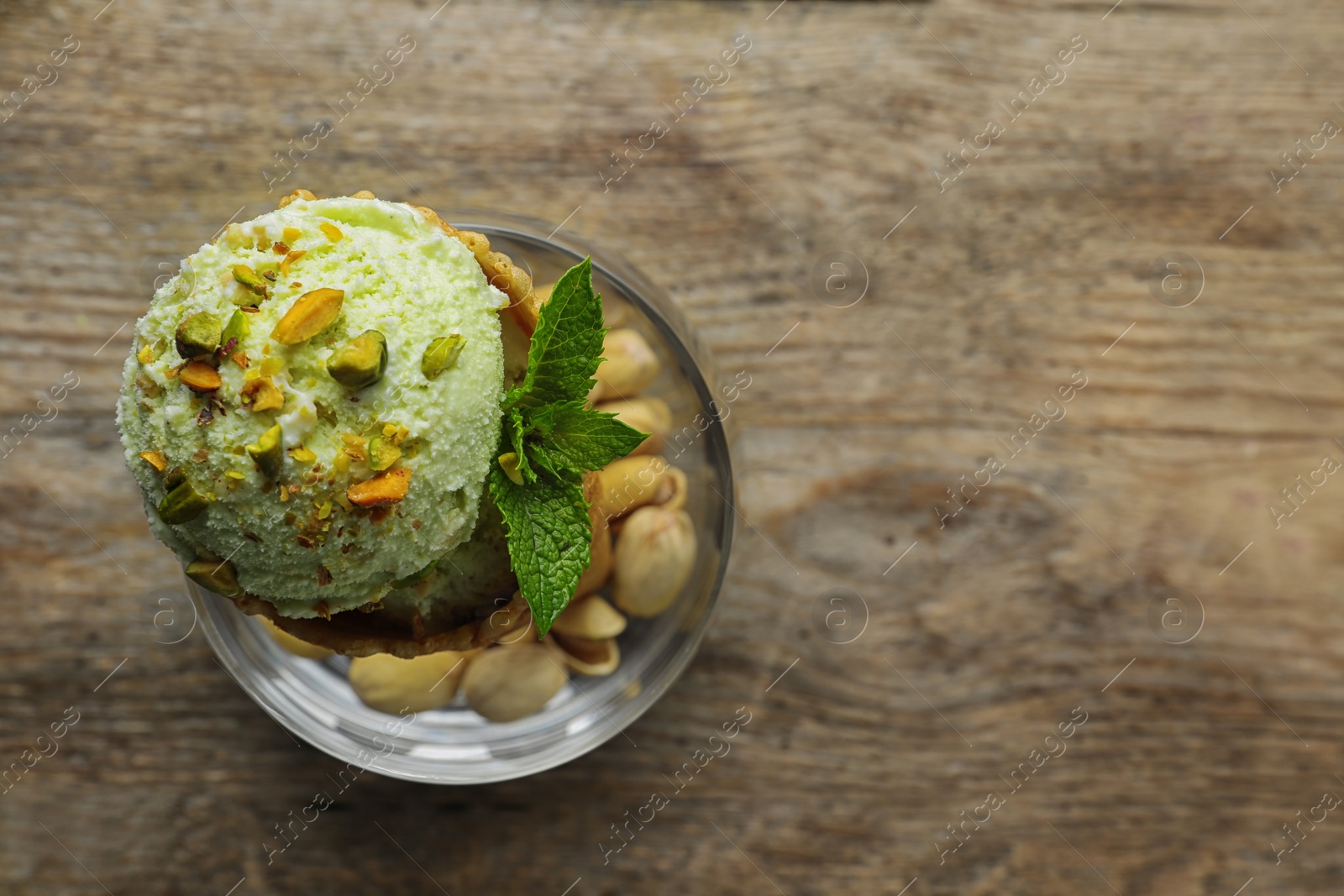 Photo of Delicious green ice cream served on wooden table, top view. Space for text