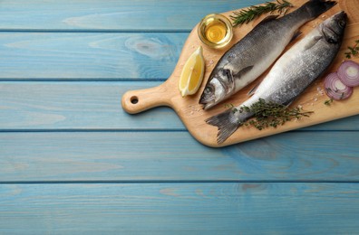 Sea bass fish and ingredients on light blue wooden table, top view. Space for text