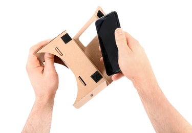 Man putting smartphone into cardboard virtual reality headset on white background, closeup