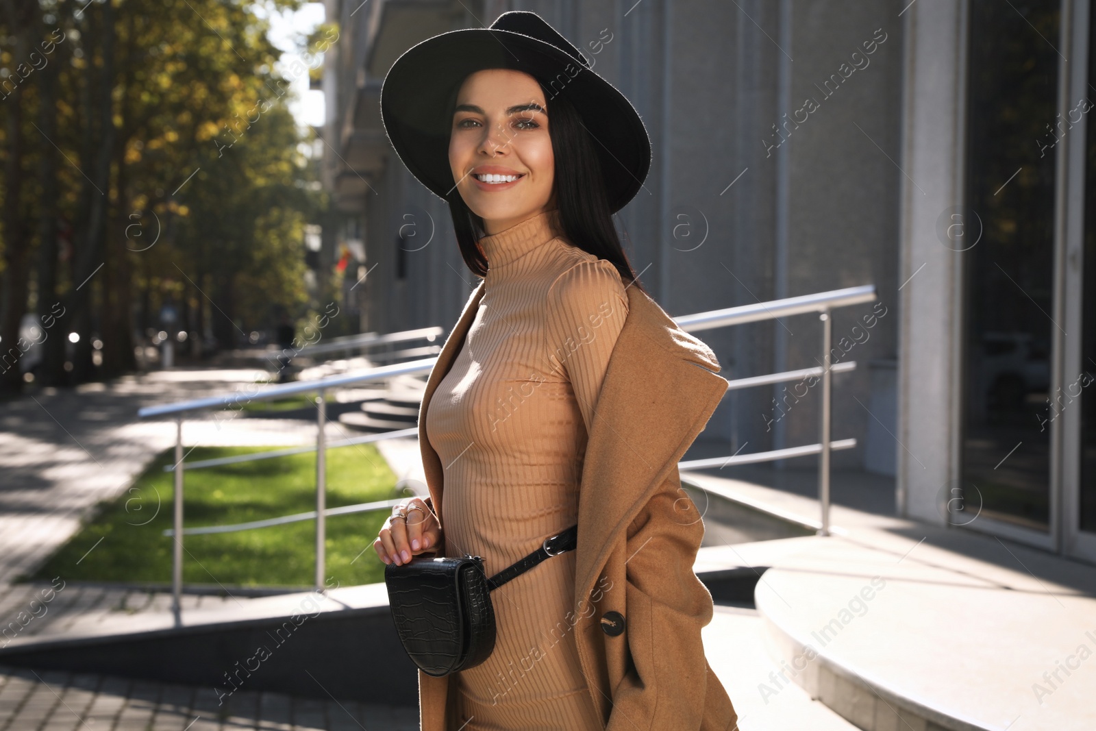 Photo of Beautiful young woman with stylish waist bag on city street