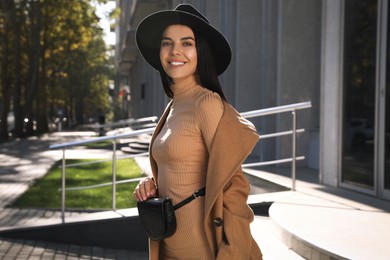 Photo of Beautiful young woman with stylish waist bag on city street