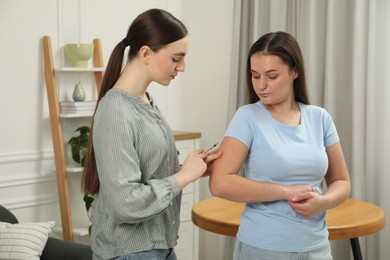 Woman giving insulin injection to her diabetic friend at home