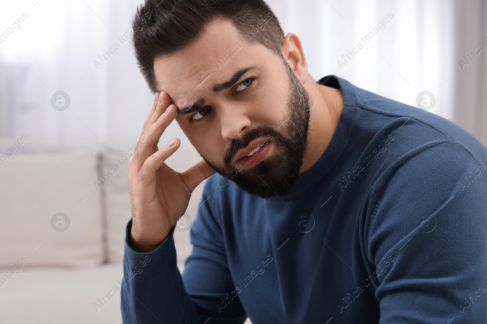 Photo of Unhappy man suffering from headache at home