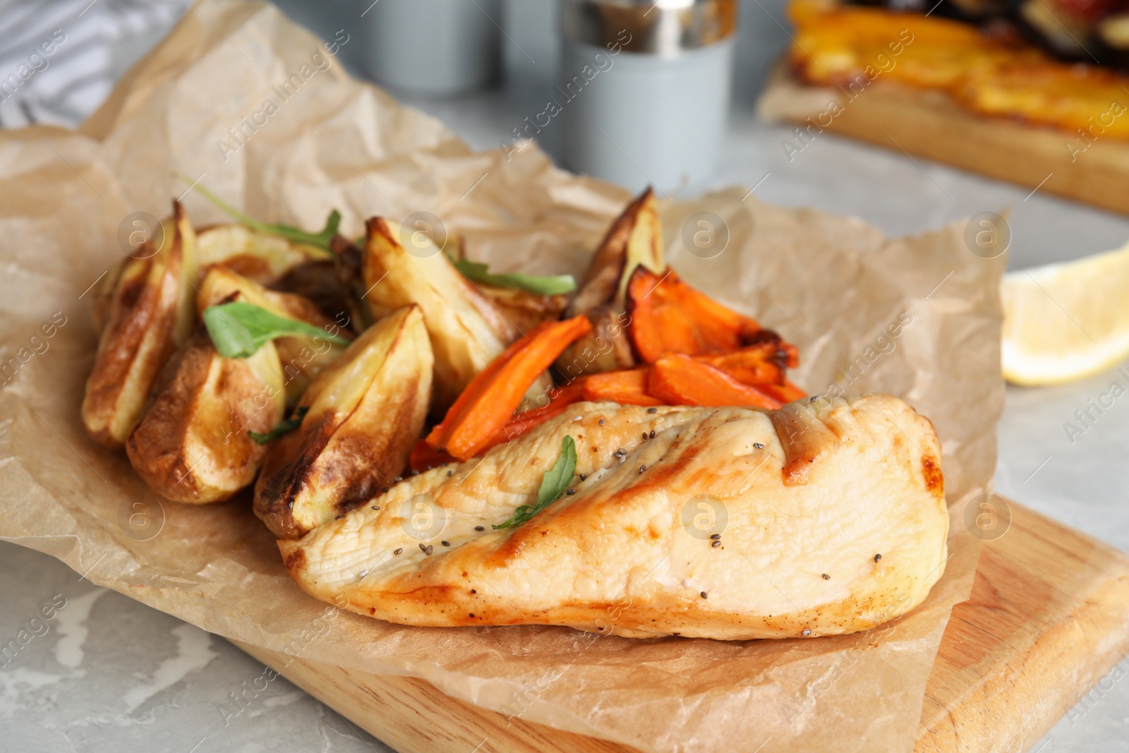 Photo of Delicious cooked chicken and vegetables on grey marble table, closeup. Healthy meals from air fryer