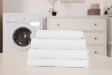 Photo of Stack of folded towels on white table in laundry room
