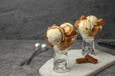 Delicious ice cream with caramel and sauce served on table