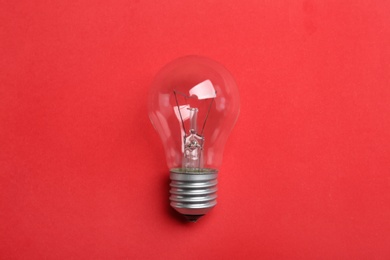 Photo of New incandescent lamp bulb on red background, top view