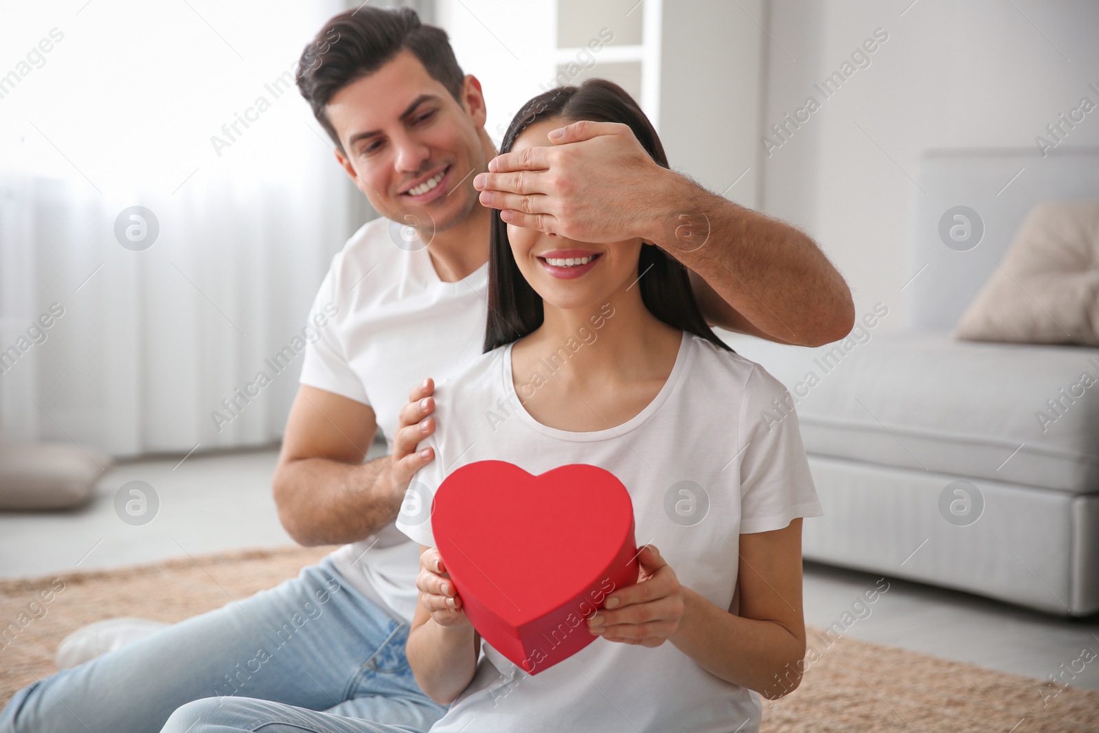 Photo of Man presenting gift to his beloved woman at home. Valentine's day celebration