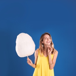 Photo of Happy young woman with cotton candy on blue background